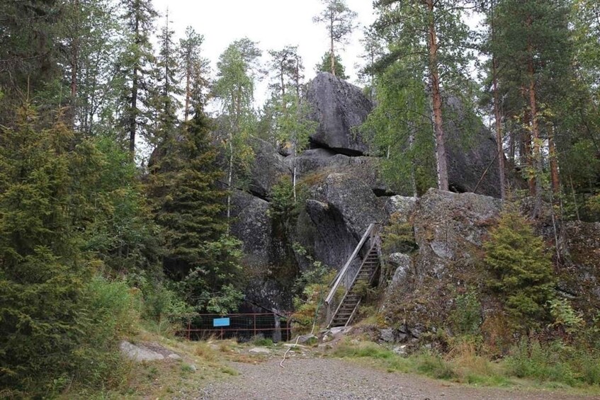 A forested area with a rocky outcrop and a staircase leading up to a higher elevation. 2