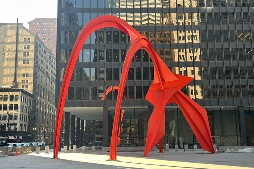 A modern building with reflective glass windows and a red abstract sculpture in front. 3