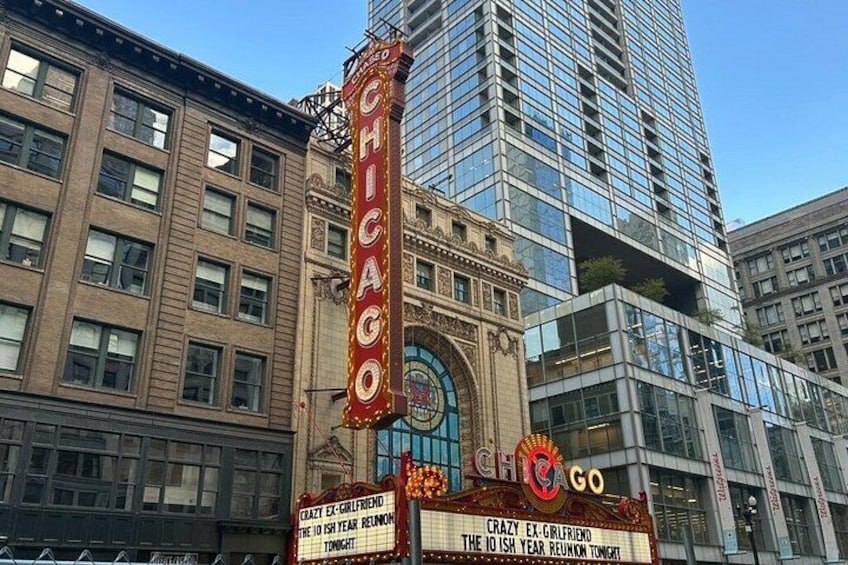 A theater marquee with 'CHICAGO' and 'CRAZY EX-GIRLFRIEND' text, a modern glass building, and a classic brick building in the background. 4