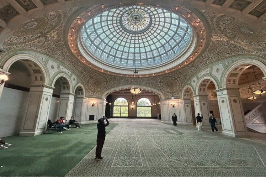 A grand hall with a large dome ceiling, ornate columns, and patterned carpet. 5