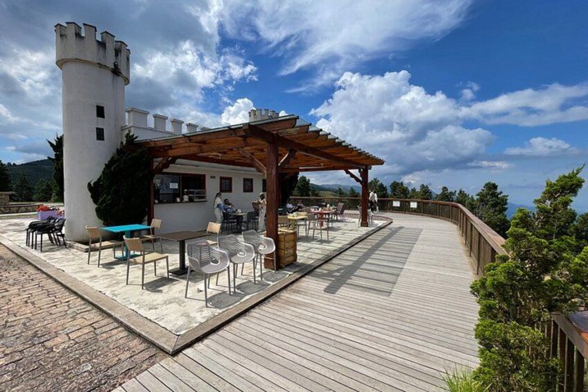 A wooden deck with outdoor seating, a castle-like structure, and a clear blue sky. 3