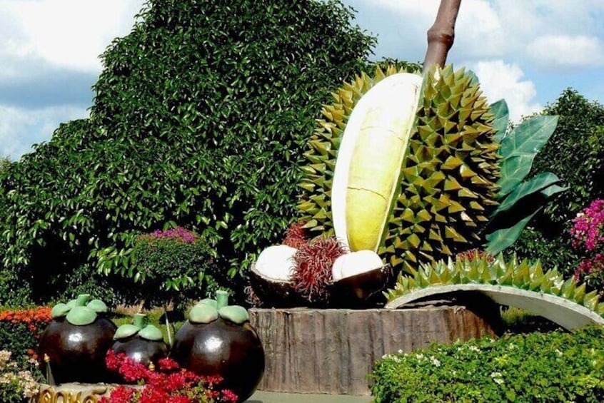 A garden with a durian tree, large decorative vases, and a wooden bench. 3