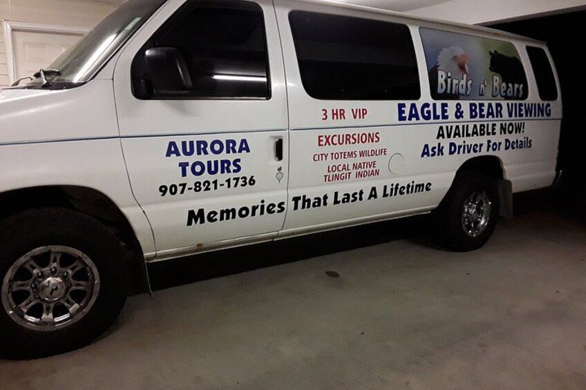 A white van with advertising for Aurora Tours, offering 3-hour VIP Eagle & Bear Viewing excursions. 2