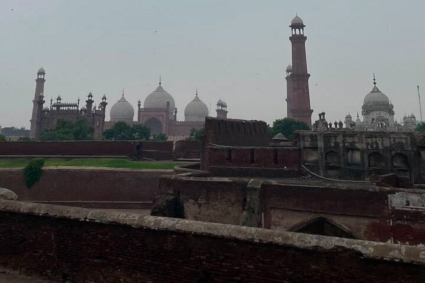 A historical building with domes and minarets, surrounded by a fortified wall. 5