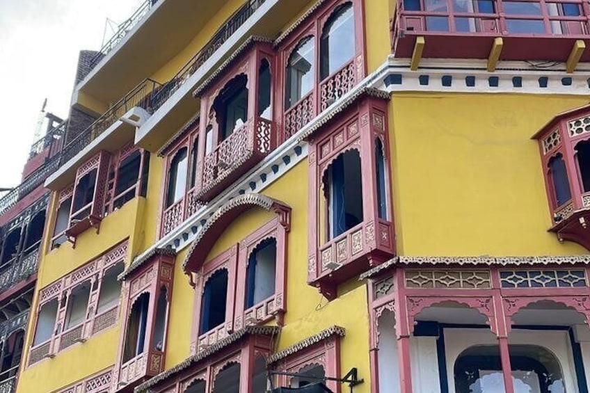 A multi-story building with traditional architectural style, featuring balconies with intricate railings and a yellow facade. 3
