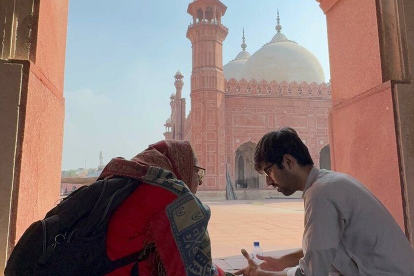 A person sitting inside a building, looking out at a large, ornate building with domes and minarets. 2