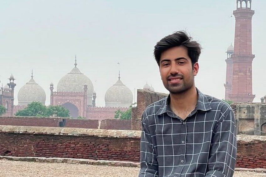 A person standing in front of a historical building with domes and a minaret. 1