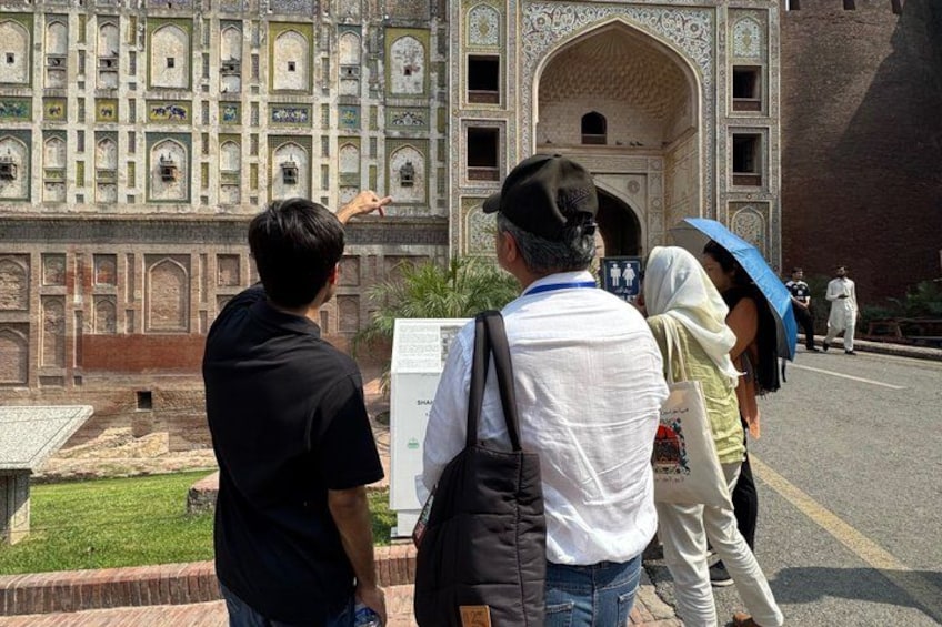 A group of people standing in front of a large, ornate building with intricate architectural details. 3