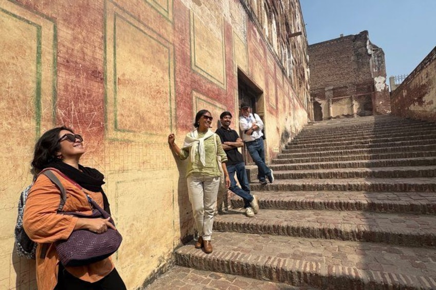 A group of people walking up a set of stone stairs in an old building with decorative patterns on the walls. 4