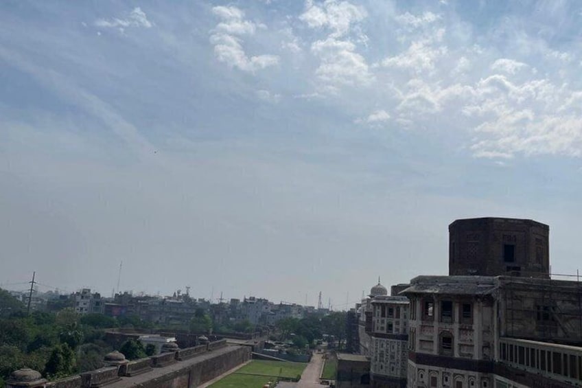 A historical fort with a watchtower, surrounded by greenery and urban buildings. 4