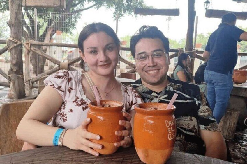 Two people sitting at an outdoor table with large clay pots. 4