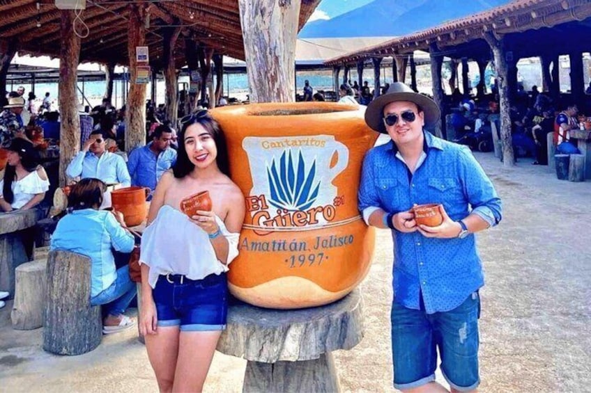 A large beer advertisement, people sitting at tables, and a tree in the background. 3