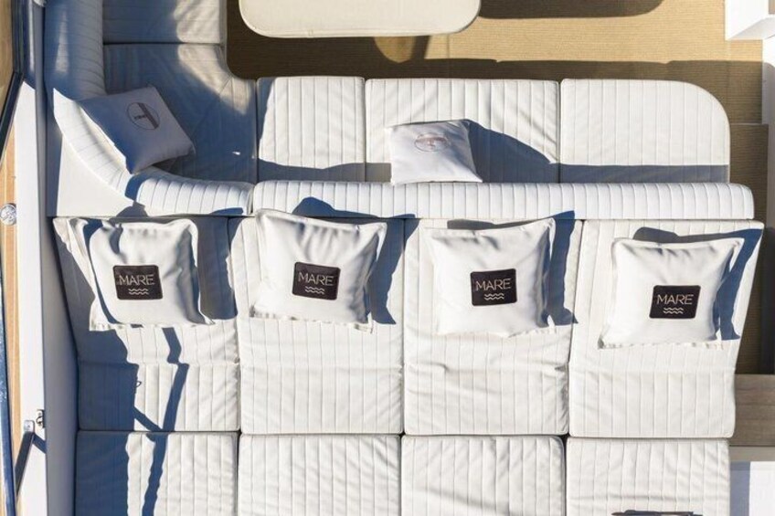 A boat interior with white striped cushions and pillows, some with 'MARE' branding. 2