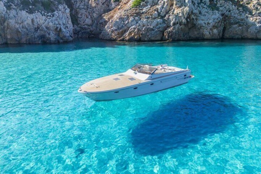 A white yacht on clear turquoise water with rocky cliffs in the background. 5