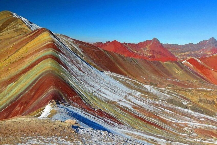 A colorful mountain landscape with distinct layers of red, yellow, and green hues. 3
