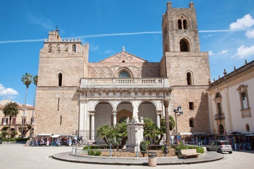 A historic building with a central dome and two towers, surrounded by palm trees and a plaza. 3