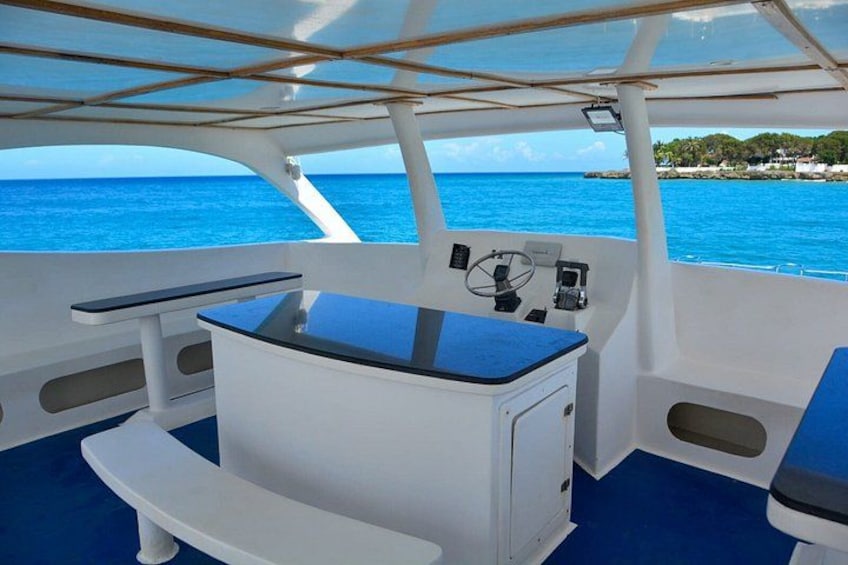 A boat's interior with a steering wheel, control panel, and seating area. 3