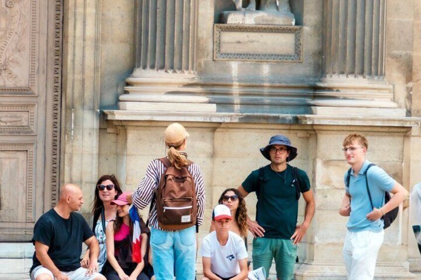 A group of people standing in front of a classical building with columns and a statue. 4