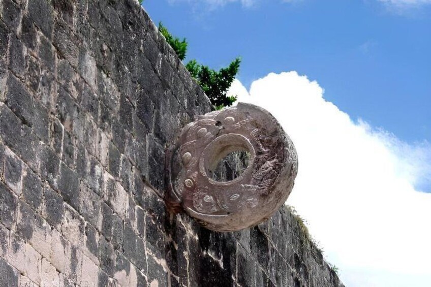 A large, circular stone structure with a hole in the center, attached to a stone wall. 5
