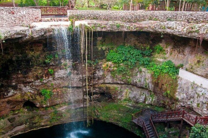A waterfall cascading into a pool, surrounded by mossy stone walls and a wooden walkway. 2
