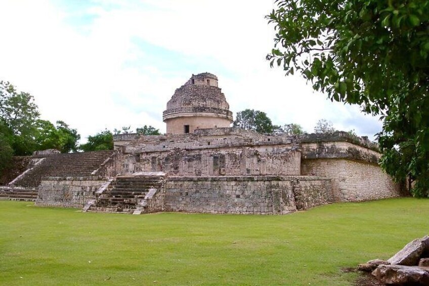 A large ancient pyramid with a stepped base and a dome-shaped top, surrounded by a grassy area and trees. 4