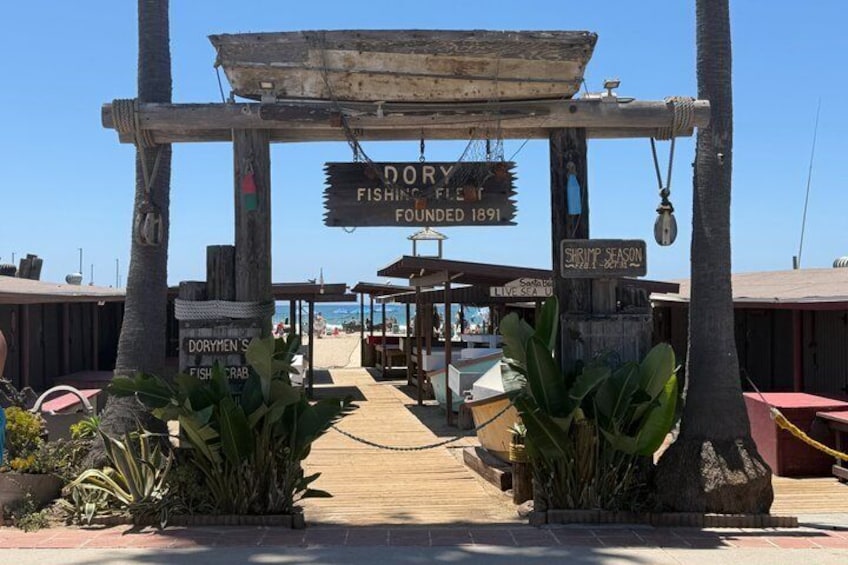 A wooden archway with signs indicating a fishing fleet founded in 1891 and shrimp season. 1