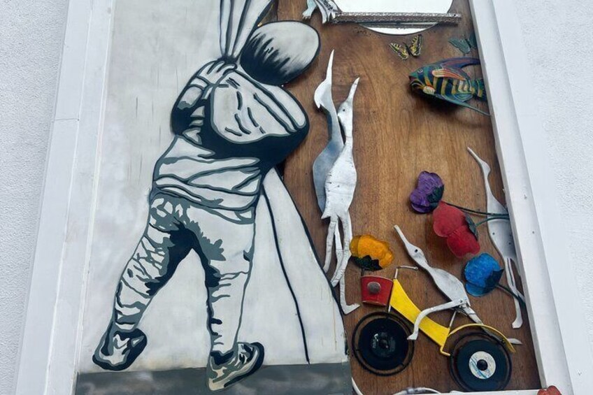 A mural of a person climbing a wall with a bicycle and colorful objects on the ground. 2