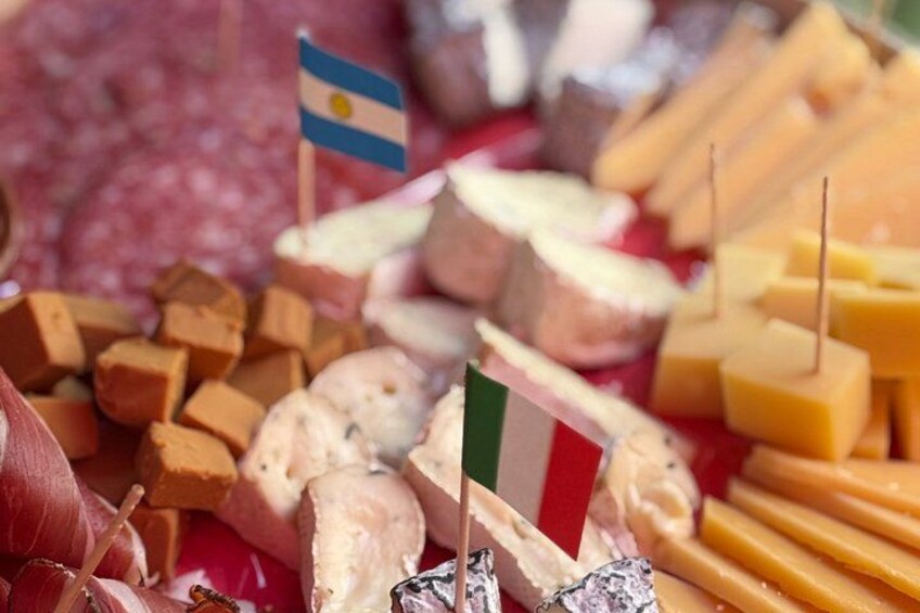 An assortment of cheeses and cured meats with small flags on top. 3