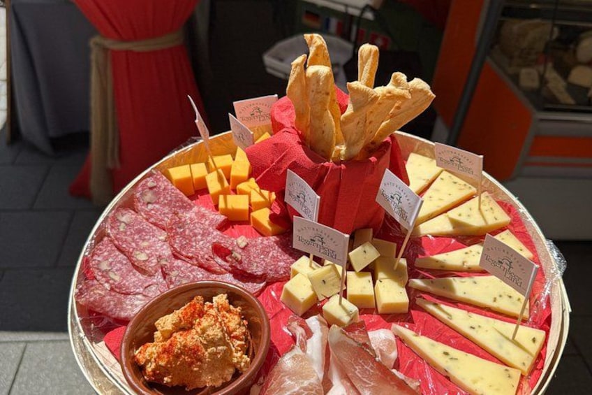 A cheese platter with various types of cheese, crackers, and a small bowl of dip. 2