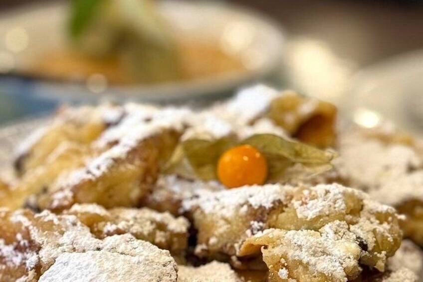 A close-up of a dessert with powdered sugar and a single orange-colored fruit. 5