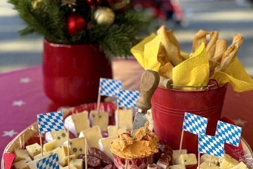 A cheese platter with various cheeses and crackers, decorated with small flags. 3