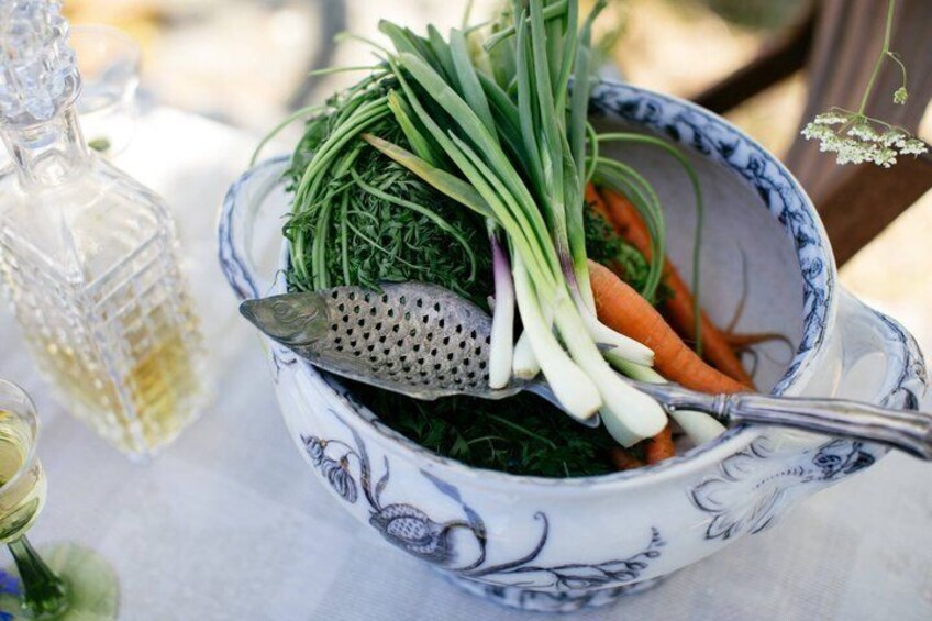 A bowl of mixed vegetables including carrots and greens, a spoon, and a glass bottle on a table. 4