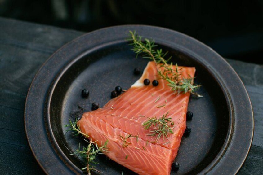 A piece of salmon on a dark plate with black peppercorns and a sprig of rosemary. 5