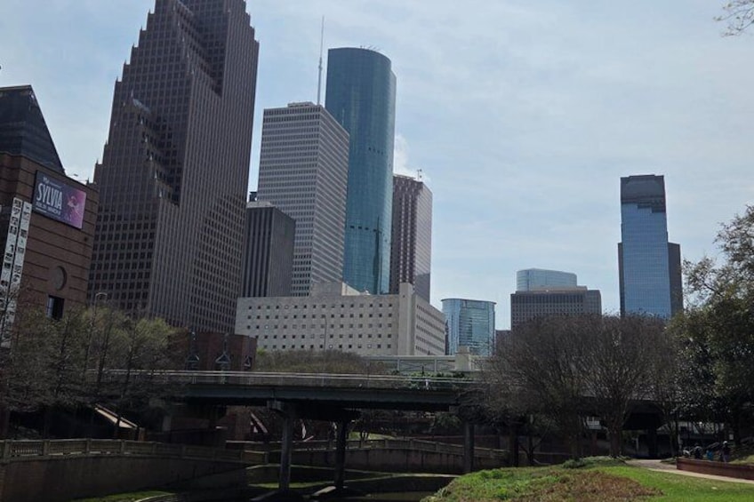 A city skyline with modern skyscrapers, a bridge, and a park area. 3