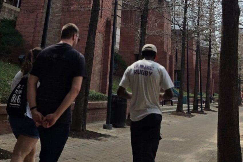 Two people walking on a brick-paved path with trees lining the sidewalk. 1