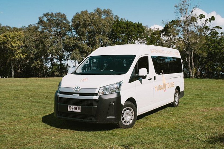 A white van with 'YURA TOURS' written on the side parked on grass with trees in the background. 4