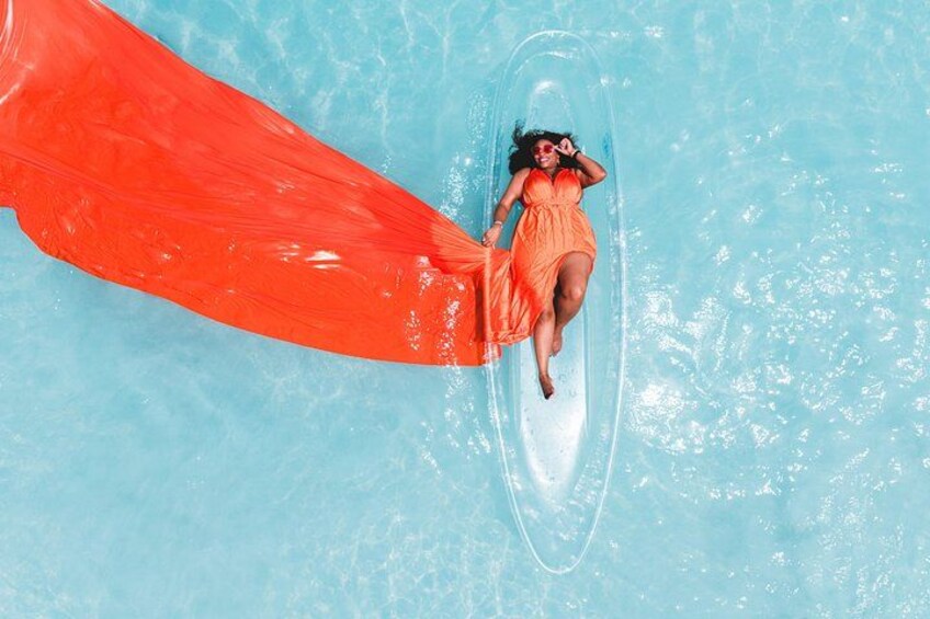 A person in a red swimsuit floating on a clear blue pool with a red inflatable tube. 2