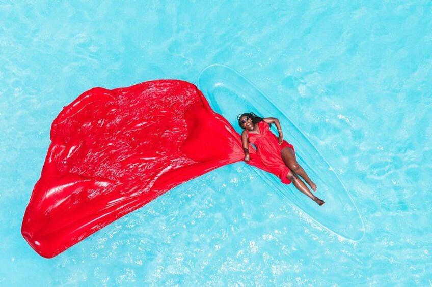 A person in a red swimsuit floating on a clear blue pool with a red object. 4