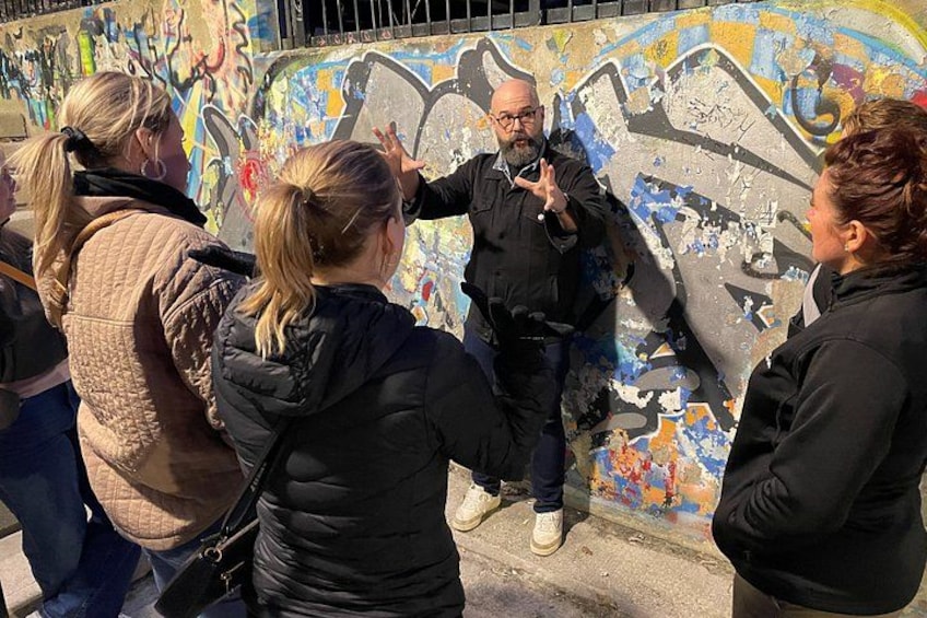 A group of people standing in front of a graffiti-covered wall. 1