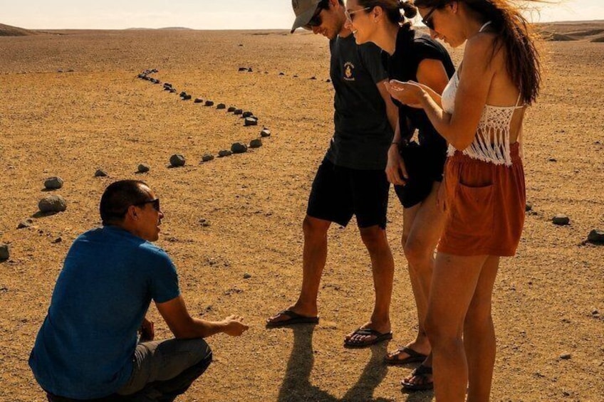 A group of people on a desert landscape with a heart-shaped arrangement of rocks. 3