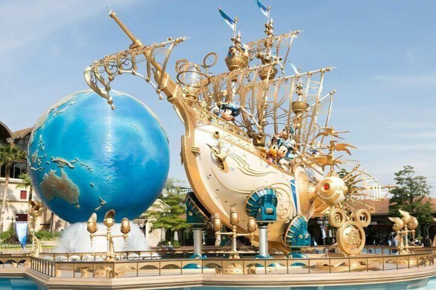 A large golden ship with Mickey Mouse figures, a blue globe, and a fountain. 1