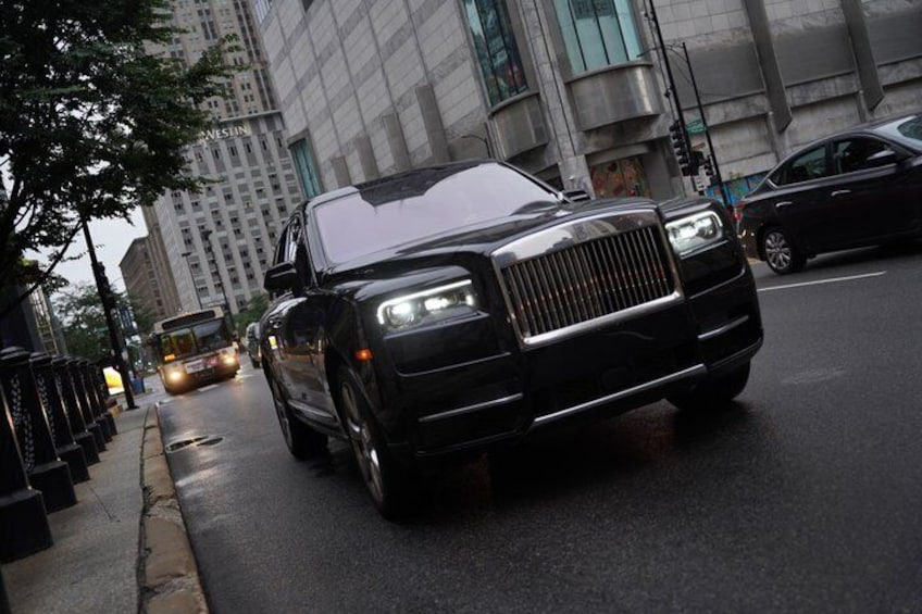 A black luxury car driving on a city street. 1