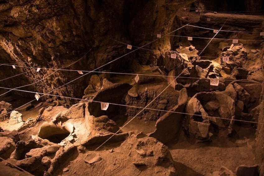 An archaeological site with exposed rock formations and excavation grids. 4