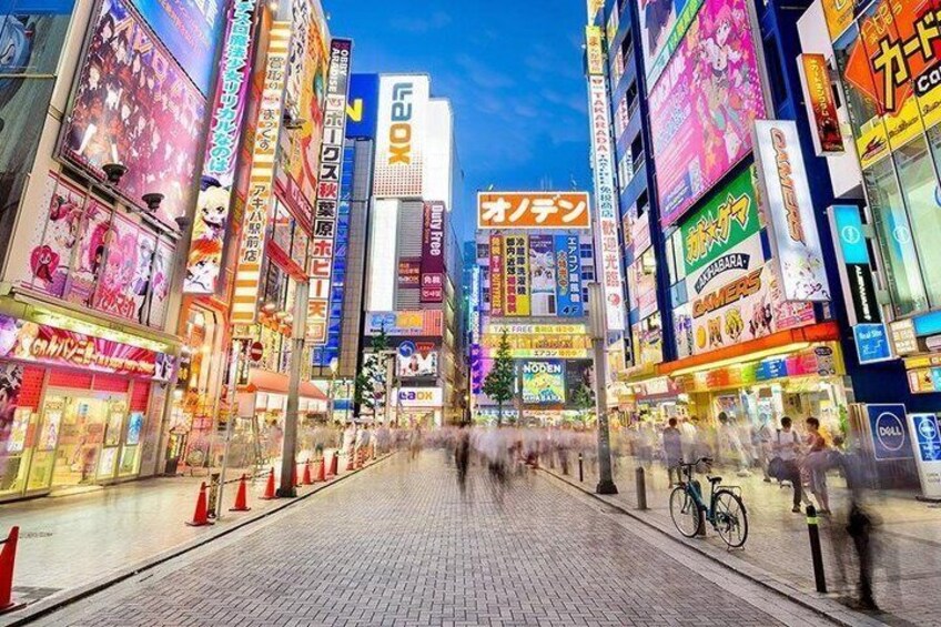 A bustling urban street lined with brightly lit commercial buildings and advertisements. 5