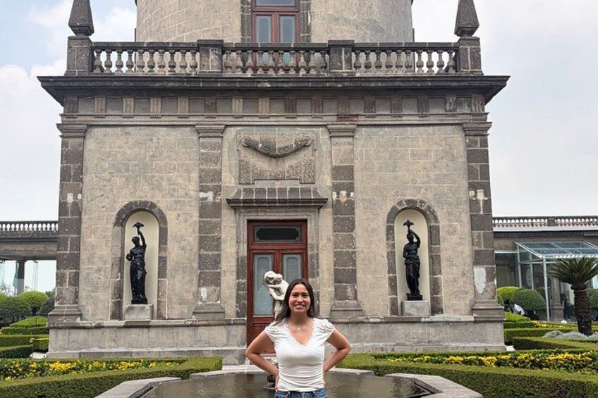 A woman standing in front of a stone building with statues and a door. 3