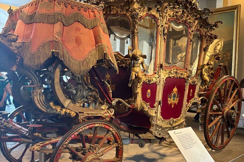 An ornate carriage with intricate gold detailing and red upholstery. 4