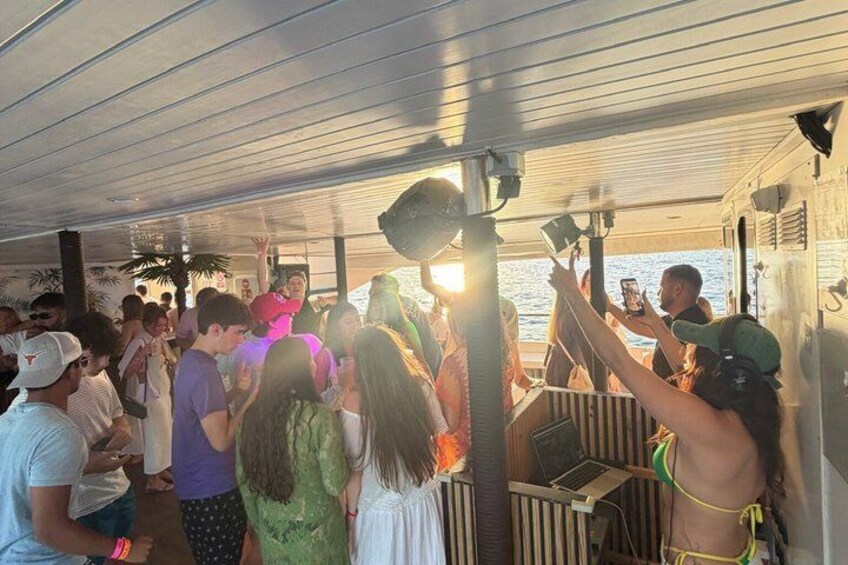 A group of people on a boat with a covered deck, some using mobile devices. 4