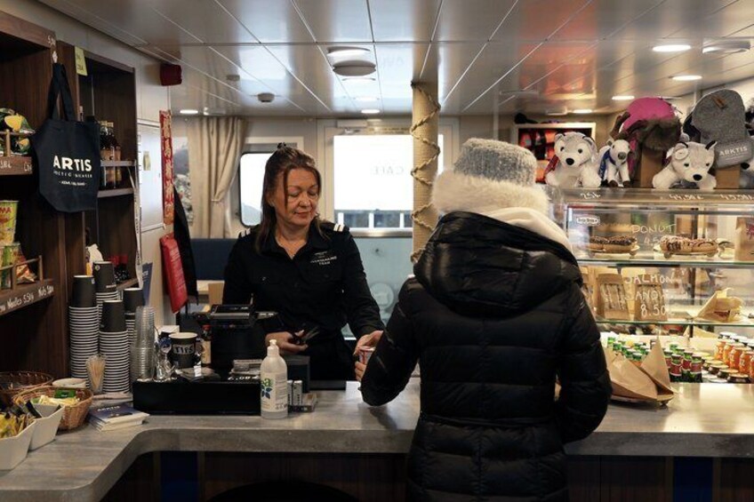 A person at a counter in a cafe, with a menu displaying items like salmon and donuts. 2