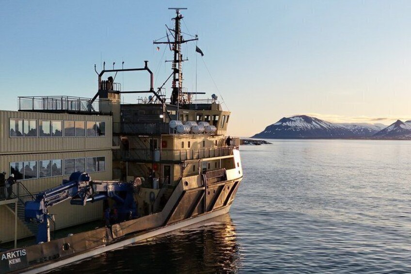 A large ship docked at a port with a mountainous landscape in the background. 4