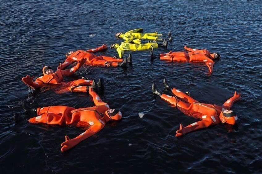 People in orange life vests floating on water. 5